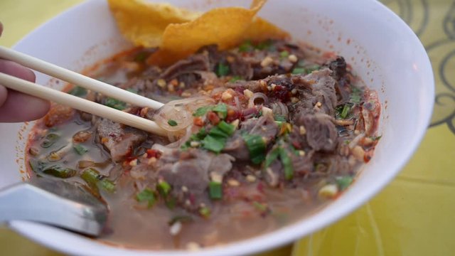 eat Stewed beef tomyum noodle with chopsticks