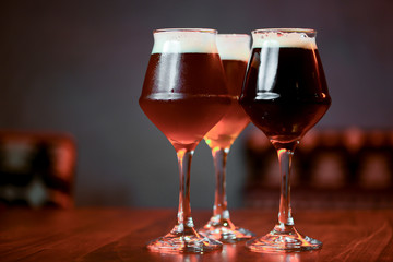 Three glasses with different beer on wooden table in a bar. Food photography concept, with copy space