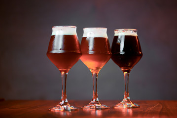 Three glasses with different beer on wooden table in a bar. Food photography concept, with copy space