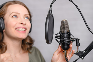 Female vocal recording. Young girl with microphone and headphones in recording studio. Recording of...