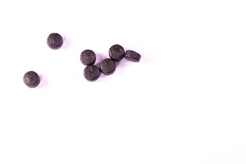 Ayurvedic medicine concept. Black ayurvedic pills and tablets scattered on white background