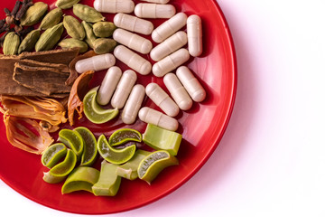 Ayurvedic medicine concept. Close-up of assorted Indian Spices with ayurvedic capsule and sliced aloe vera in a plate on white background