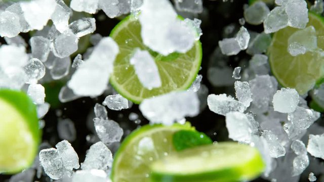 Super Slow Motion of exploding crushed ice with limes towards camera, close-up