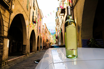 Primo piano di una bottiglia di vino bianco appoggiata sul tetto di una macchina nel viale dei...