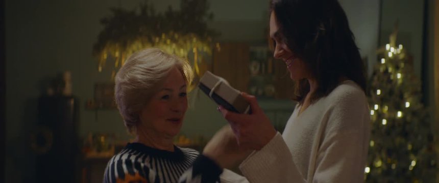 Adult daughter giving elderly mother a hug as multi generation family celebrate Christmas at parents home. Shot on ARRI Alexa Mini with Cooke 2x Anamorphic lenses. 4K UHD RAW Graded footage