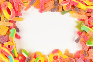 Frame of assorted gummy candies isolated on white. Top view. Space for text or design.