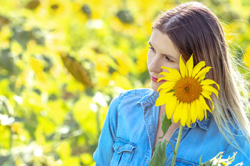 Outdoor portrait of beautiful young woman in field of sunflowers, lifestyle girl hiding behind flowers
