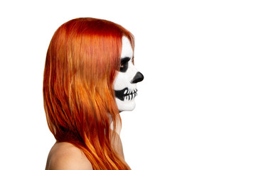Side view portrait of a young girl with Halloween skull makeup in a black hoodie with red hair