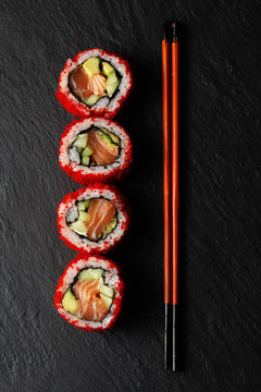 Sushi roll with salmon, avocado, roe, chopsticks