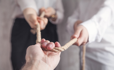  Business people pulling rope in office.