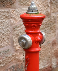Roter Hydrant mit silbernen Schlauchanschlüssen