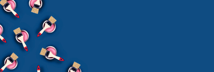 Renovation concept. Classic blue background with pink paint cans and brushes located on them. Flat lay, top view, copy space.