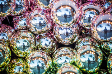 Sparkling shiny green and purple Christmas ornaments with reflection of person