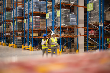 Positive cheerful warehouse workers checking organization and distribution of products in large...