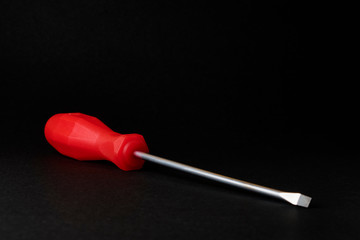 screwdriver with red handle on black background