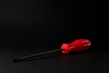 screwdriver with red handle on black background