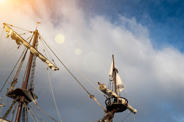 Masts and rigging of old pirate ship on background of cloudy blue sky