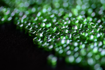 Seed beads green color scattered on a dark background close-up