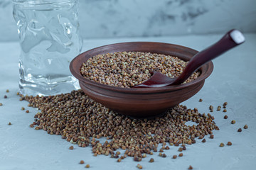 Buckwheat raw, medium rare. Measured for making porridge. On a gray background under concrete.