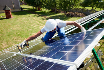 Professional worker installing solar panels on the green metal construction, using different...
