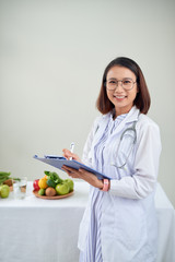 Female nutritionist with fruits working at her desk