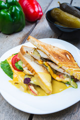 Classic breakfast, hot sandwiches with cheese, vegetables and chicken on a wooden table.