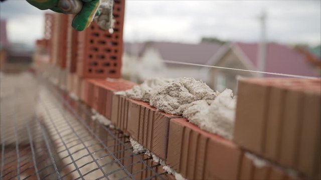 Profesional worker builds an expensive red brick house. Laying of red bricks