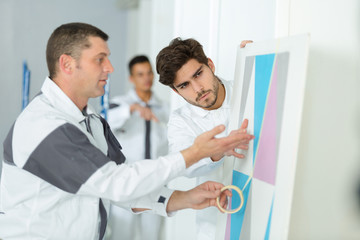 man and apprentice applying a masking tape before paint