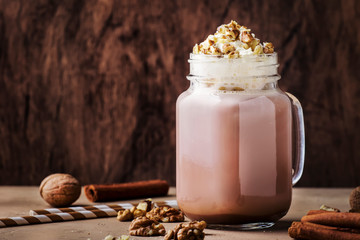 Winter hot dark chocolate with whipped cream and crushed walnuts in glass jar, copy space