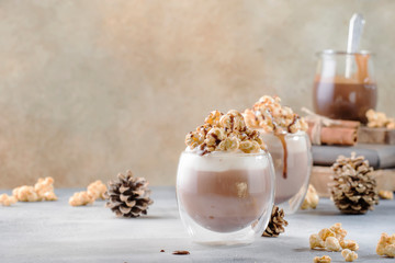 Cold chocolate dessert with whipped cream, popcorn and caramel topping in glasses on beige background, place for text