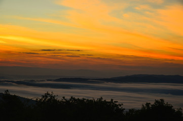 Stunning amazed natural landscape of sun rising above mountain and sea of mist in the fresh morning on high mountain in Thailand.