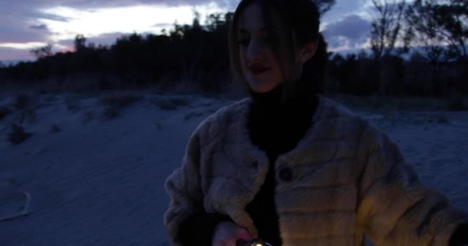 Ragazza va in giro in bicicletta di notte sulla spiaggia. Striscia illuminata di luci led.