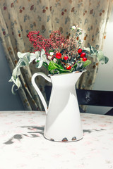 old white enameled milk jug with flowers and berries