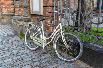 Fototapeta na wymiar White Bicycle parked at the old Church's cast-iron grating