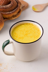 healthy drink golden milk next to breakfast rolls. vertical photo