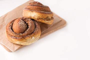 two cinnamon rolls on a wooden board on a white background. copy space