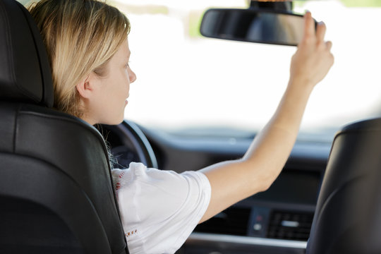 Woman Adjusting Her Rearview Mirror In The Car