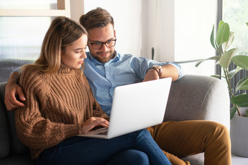 Young couple ordering online, looking in laptop	 - obrazy, fototapety, plakaty