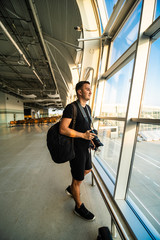 Young man blogger photographer making a photo of jet at runway before taking off. Concept of modern travelling and blogging.