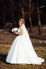 Obraz na płótnie Canvas Beautiful luxury bride in elegant white dress. Gorgeous beautiful bride smiles while posing with bouquet. Beautiful stylish bride with bouquet in hand