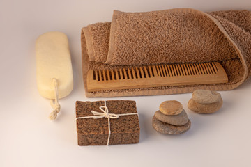 Spa and wellness concept, natural coffee scrub soap, essential oil cosmetic, peeling sand stone, towel, natural wooden haircomb. Beige brown dayspa set copyspace. Pastel bathroom accessories products.