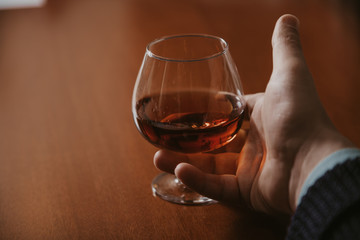 Hand holds glass with cognac close-up