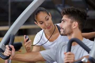 female gym trainer holding timer inspecting client