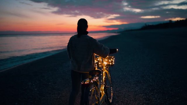 San Valentino, la festa degli innamorati. Ragazza da sola in bici la notte vicino al mare