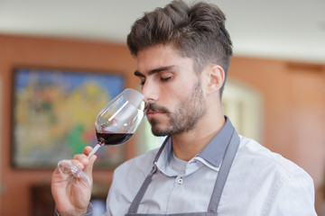 a male waiter is smelling wine