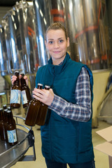 female brewery worker with bottling machinery on factory