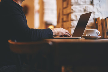 Man working on his laptop on a bar chair in a cafe by the window