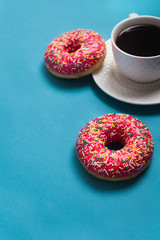 A cup of americano with two pink donuts on a blue background