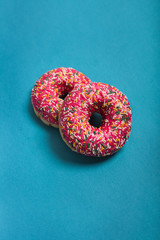 A cup of americano with two pink donuts on a blue background