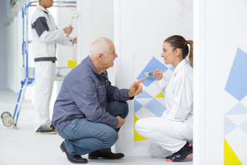 mature painter with young female apprentice holding paintbrush